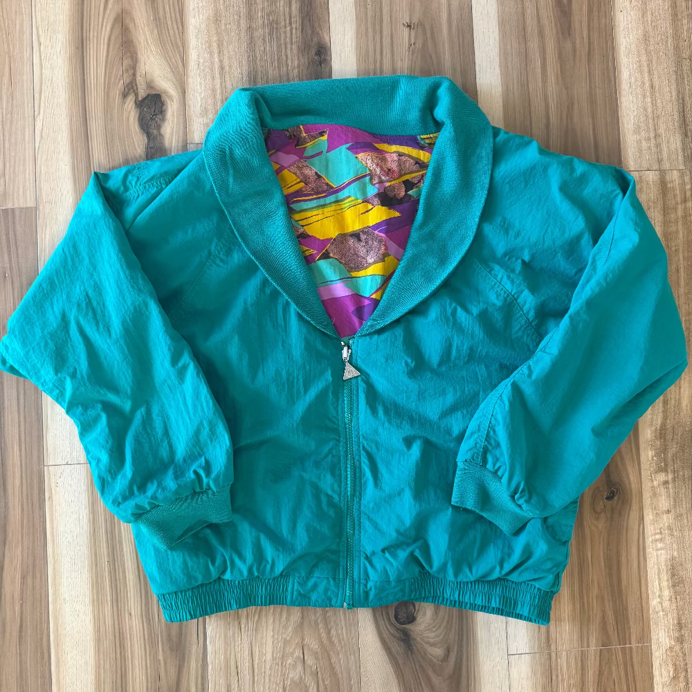 Teal jacket with colorful lining on a wooden surface