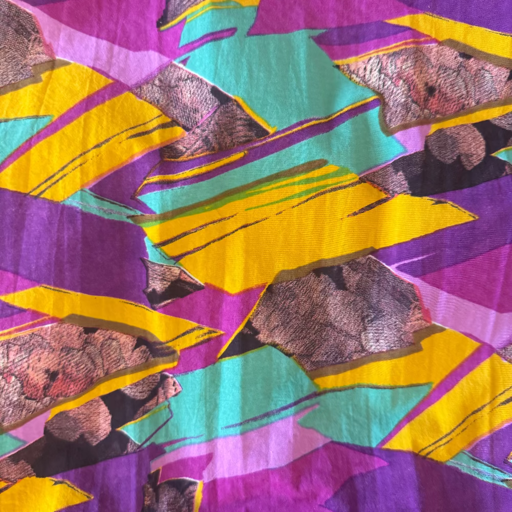Colorful fabric with abstract pattern featuring purple, yellow, and teal.