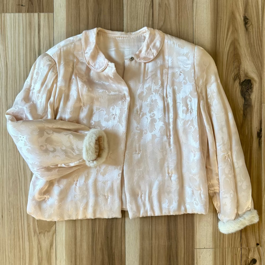 Light pink jacket with white fur trim on a wooden floor