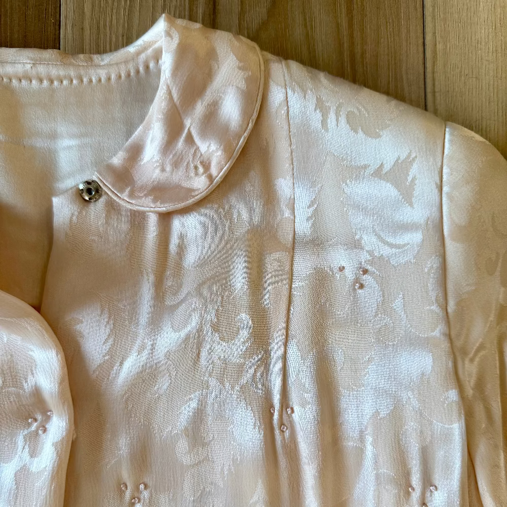 blush pink silk jacket against wood floor background